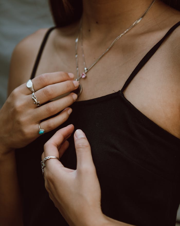 Close-up of a woman's hands showcasing delicate silver rings and necklace.